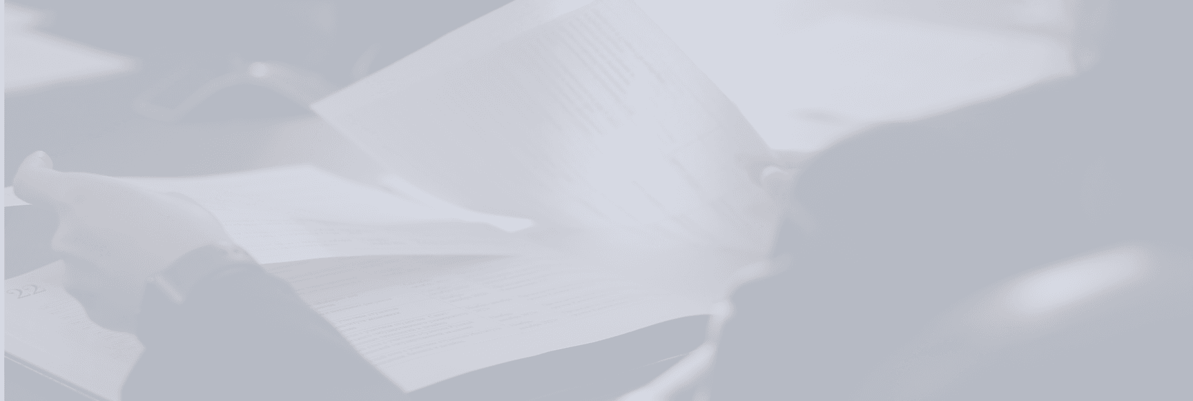 A person's hands turning the pages of a book or document with faint, blurry text visible.